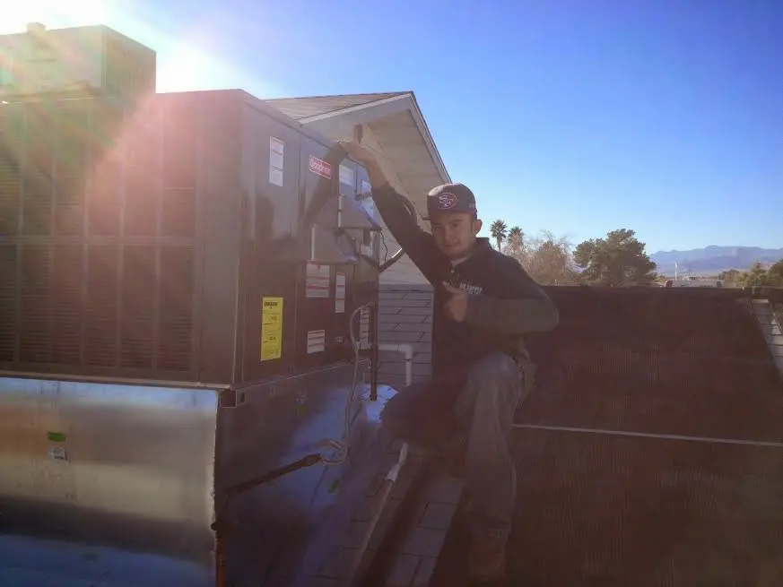 HVAC technician performing AC Tune-Up on a rooftop unit in Medfield